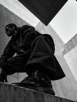 Model crouching on concrete in black BLACK essentials